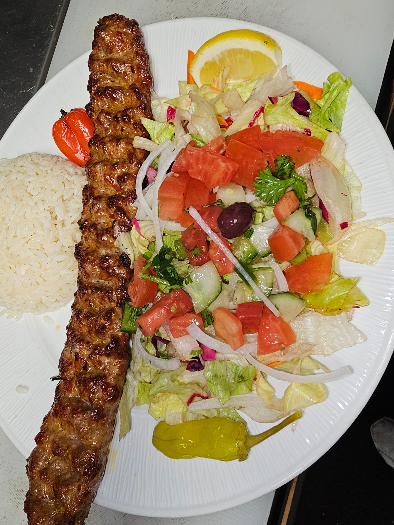 Adana kebab long skewer with house salad and rice