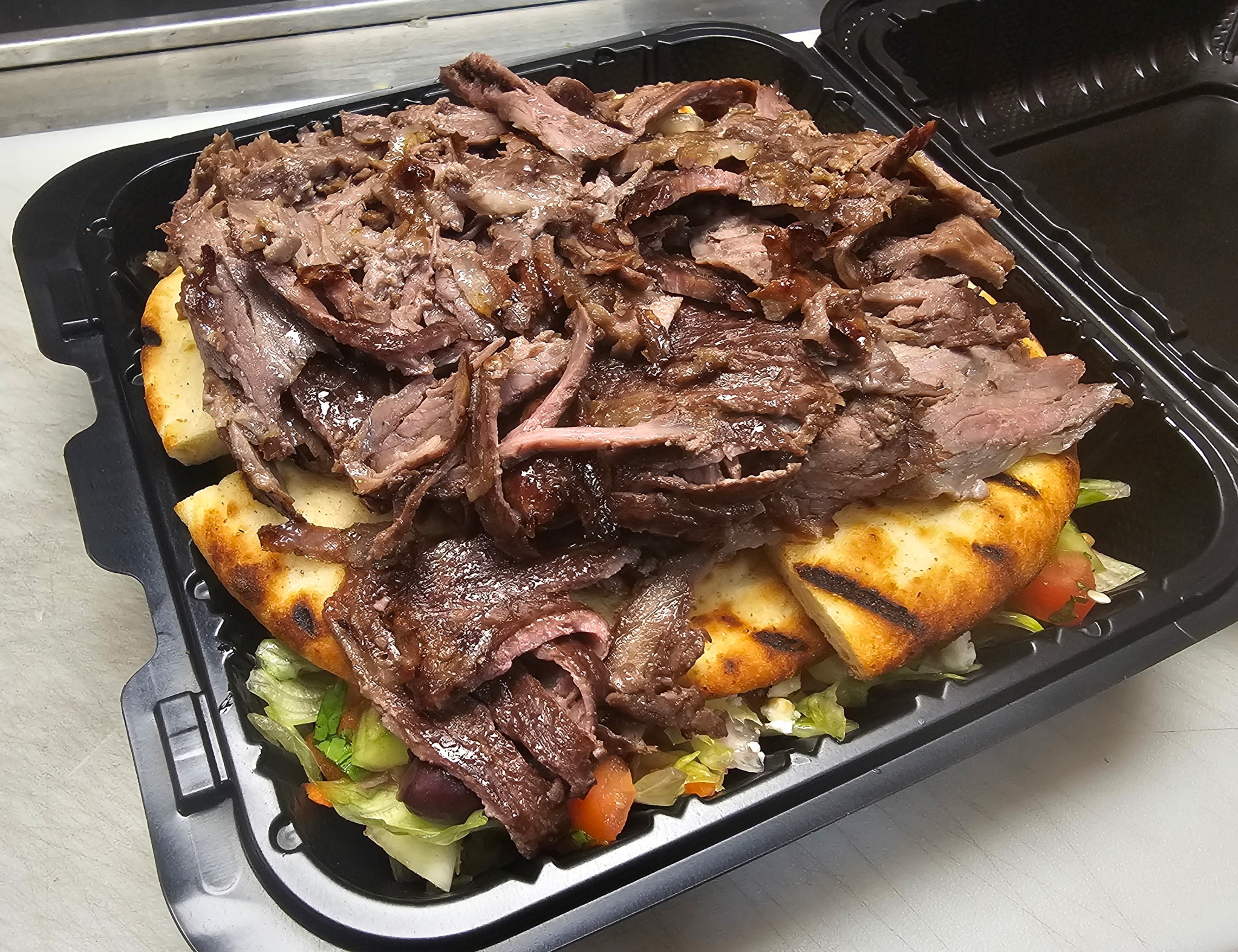 Slow-cooked lamb shank over grilled flatbread and salad